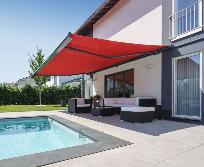 Overkapping met een rood zonweringdoek bij een zwembad in een moderne terrassensituatie.
