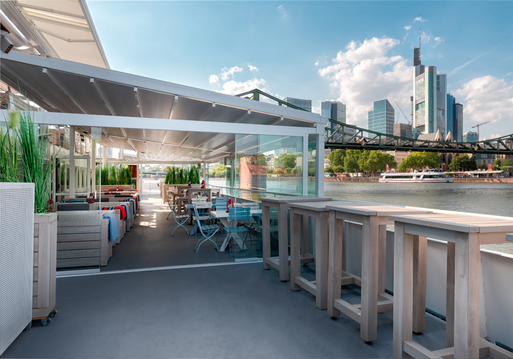 Landschaft mit Überdachung, Terrassensituation und Blick auf eine moderne Stadtlandschaft.