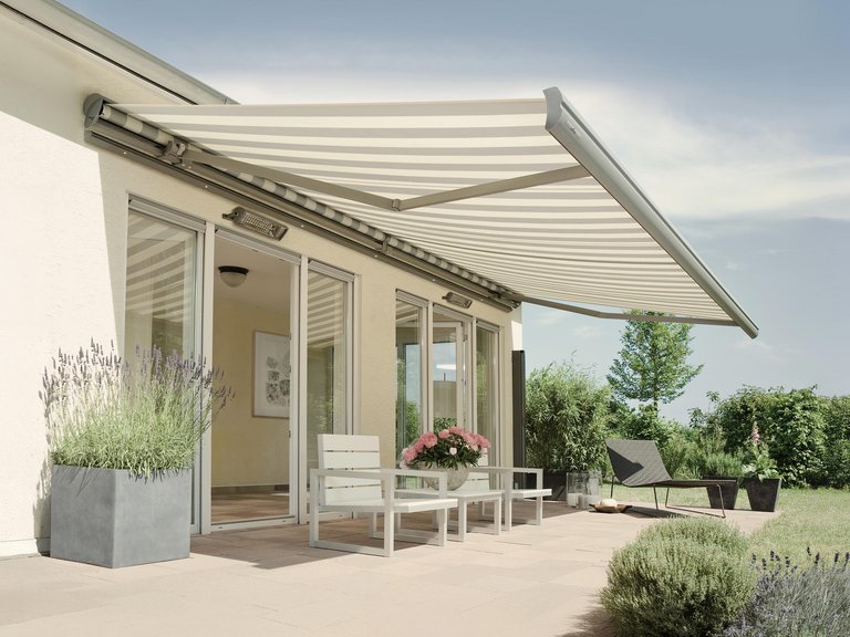 Markise über einer Terrassensituation mit Pflanzen in Kübeln und einer Überdachung im Hintergrund.