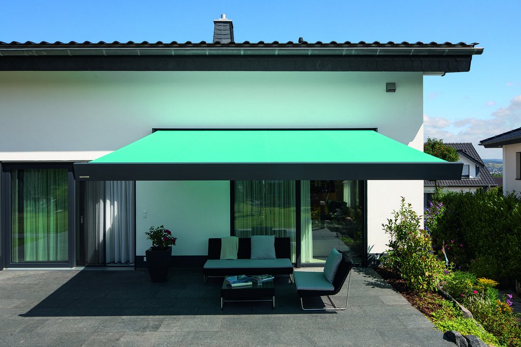 Een woning met een groene zonnescherm die een terrassensituatie overspant. Een woning met een groene zonnescherm die een terrassensituatie overspant.