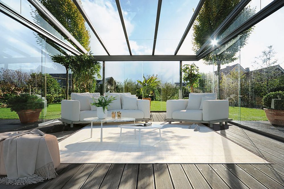 Moderne serrezonnescherm met glazen wanden, lichte meubels en groene planten met een natuurlijke omgeving. Moderne serrezonnescherm met glazen wanden, lichte meubels en groene planten met een natuurlijke omgeving.