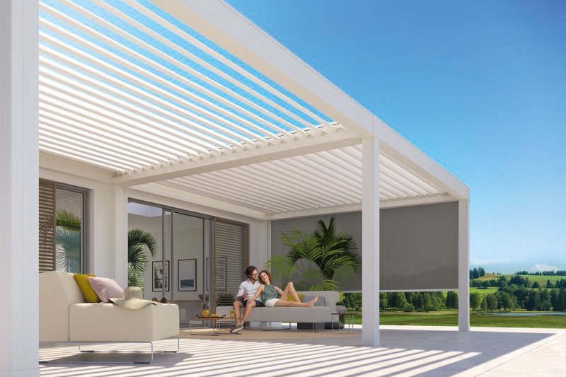 Terrassensituatie onder een moderne overkapping met schaduwdoeken en uitzicht op groene velden. Terrassensituatie onder een moderne overkapping met schaduwdoeken en uitzicht op groene velden.