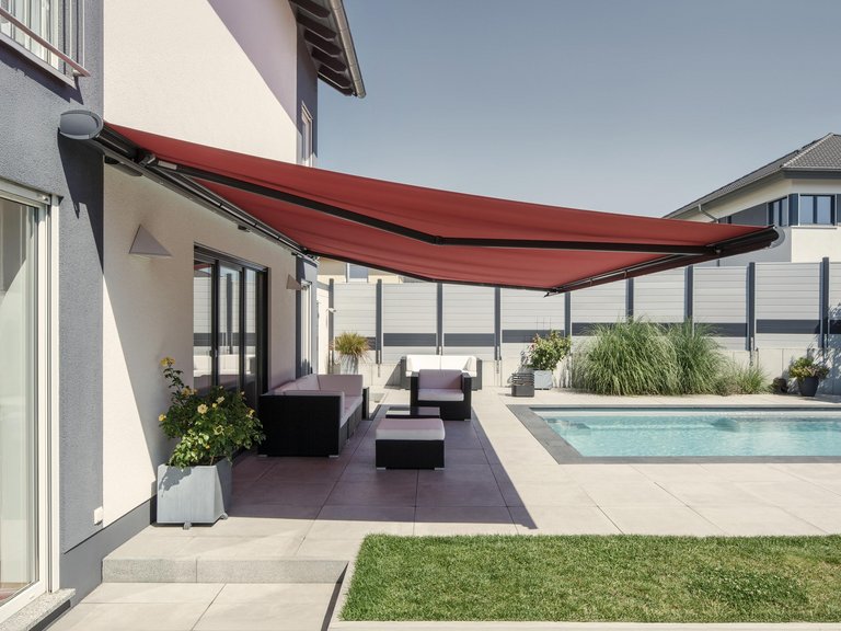 Terrassensituation mit roter Markise über einem Pool und einem gepflegten Gartenbereich.