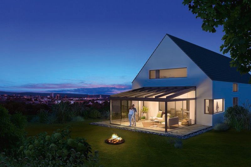 Moderne woning met glasoverkapping en terras in een groene omgeving, 's avonds verlicht. Moderne woning met glasoverkapping en terras in een groene omgeving, 's avonds verlicht.
