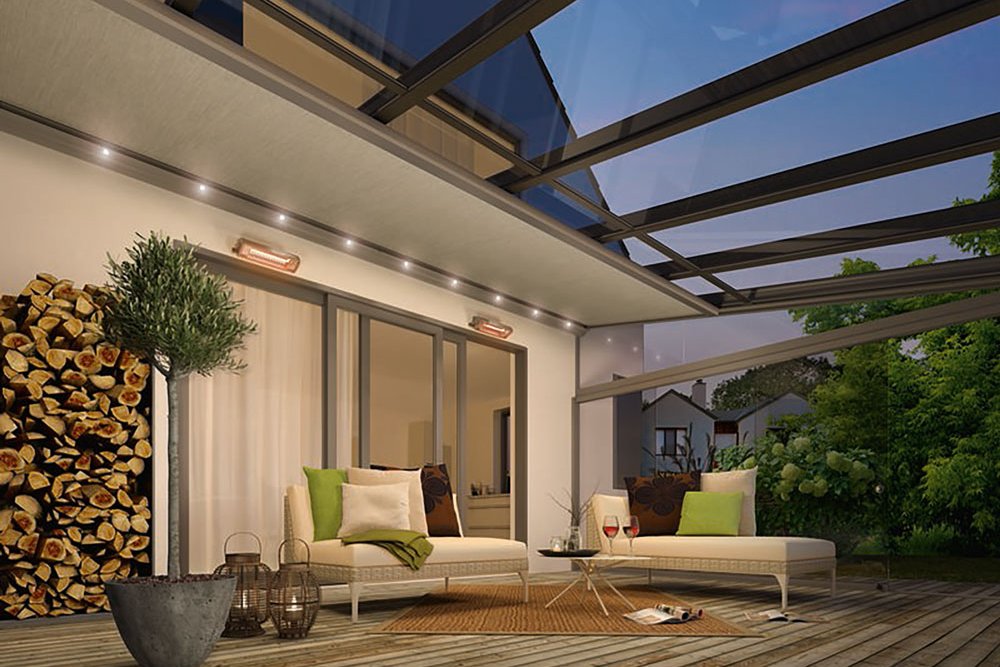 Terrassensituatie met een overkapping en glazen elementen, verlicht door sfeerverlichting bij schemerlicht.