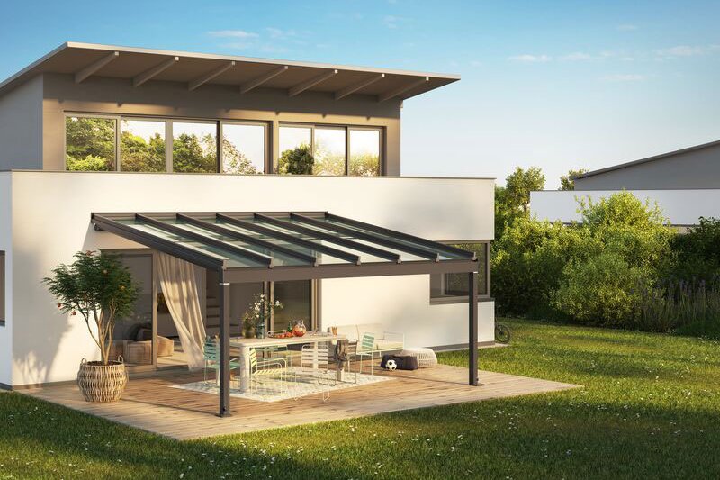 Moderne woning met een overkapping en terras in een groene omgeving onder een blauwe lucht. Moderne woning met een overkapping en terras in een groene omgeving onder een blauwe lucht.