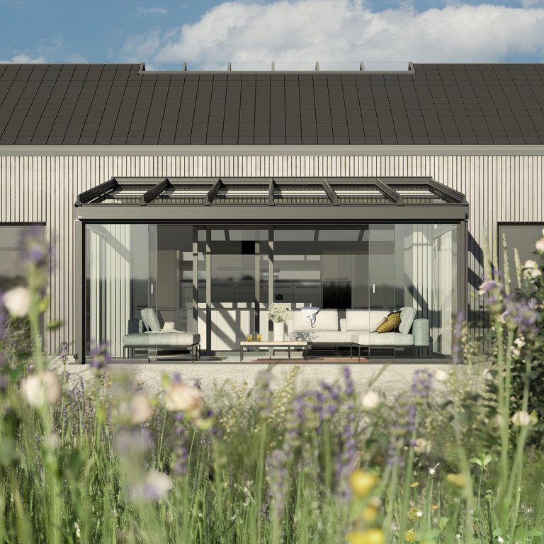 Moderne Hausfassade mit Glas-Schiebewänden und einer Überdachung, umgeben von bunten Blumen.