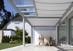 Terrassensituatie met een overkapping, glazen schuifwanden en een eettafel met stoelen.