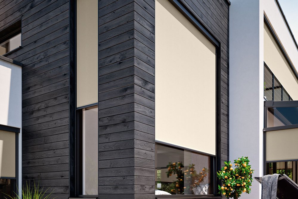 Moderne woning met zwarte gevel, grote ramen en beige zonneschermn aan de gevel. Terrassensituatie met planten. Moderne woning met zwarte gevel, grote ramen en beige zonneschermn aan de gevel. Terrassensituatie met planten.