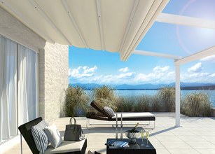 Moderne terras met een overkapping en uitzicht op het water, onder een heldere blauwe lucht. 