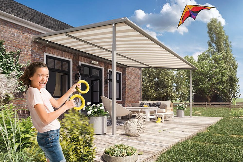 Een meisje met een glimlach speelt met ringen onder een overkapping op een terras. Blauwe lucht en wolken. Een meisje met een glimlach speelt met ringen onder een overkapping op een terras. Blauwe lucht en wolken.