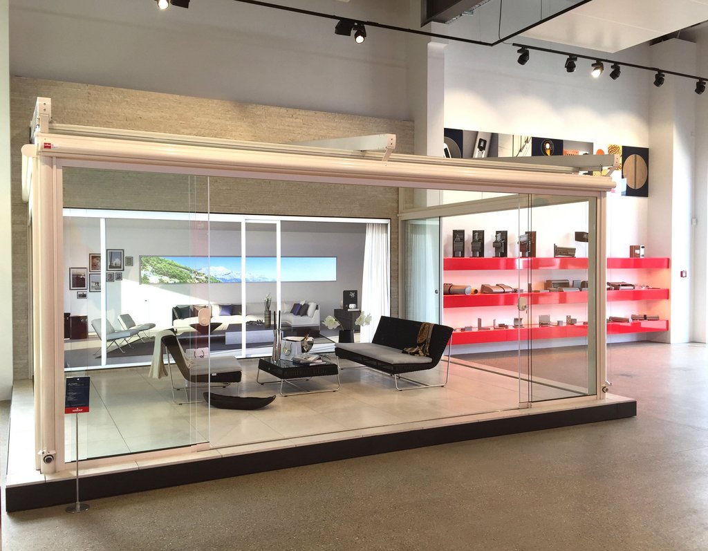 Moderne overkapping met glazen wanden in een showroom, afgewerkt in wit en zwart.
