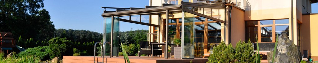 Moderne woning met glazen elementen en een overkapping, omgeven door groene planten en een terras. Moderne woning met glazen elementen en een overkapping, omgeven door groene planten en een terras.