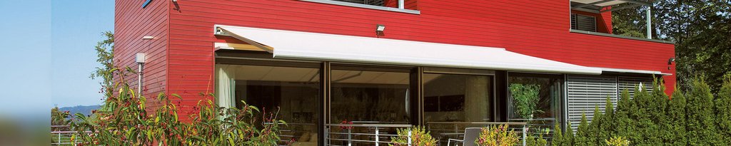 Een moderne woning met een rode gevel en een overdekte terrassituatie.