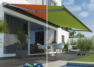 Een afbeelding van een terras met een oranje en groene zonnescherm die uitgestrekt zijn. 