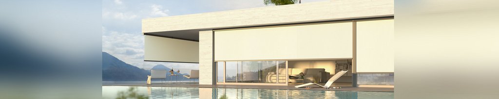 Moderne woning met een overkapping en glazen schuifwanden langs een waterpartij en bergen op de achtergrond.