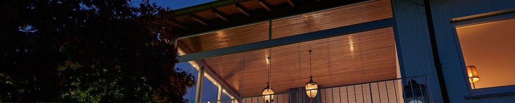 Terrassensituatie bij nacht, met een houten constructie en sfeervolle verlichting.